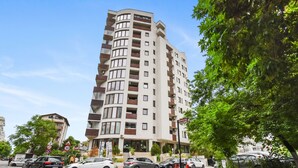 A multi-story residential building with balconies, a parking area, and a clear sky. - 1BDR Apartment close to Unirii Square (Bucharest)