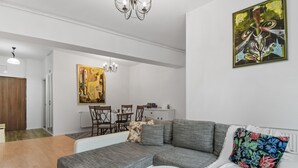 A modern living room with a sectional sofa, a small round table, and a dining area with chairs and a table. - 1BDR Apartment close to Unirii Square (Bucharest)
