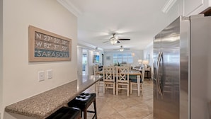 A kitchen with a granite countertop, a refrigerator, a dining area with a table and chairs, and a ceiling fan.