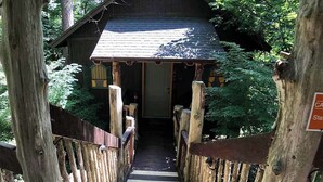 A wooden cabin with a porch, surrounded by trees. - Chateau Treehouse #11/ Oak Crest (Eureka Springs)