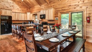 Una baita di legno con cucina, sala da pranzo e un'ampia porta-vetrina che si apre su un patio.