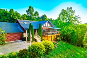A cabin with a balcony, surrounded by lush greenery and trees. - NEW! Private 5BR, Sleeps 18, Six person Hot tub, Game Rm, Arcade (Sevierville)