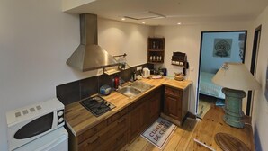 Une cuisine de taille réduite, dotée de meubles en bois, d’une cuisinière à gaz, d’un four à micro-ondes et d’un évier.