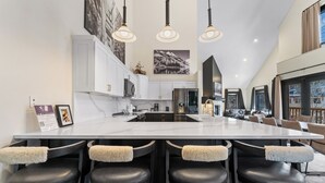 A modern kitchen with a large island, bar stools, and pendant lighting. - Arapahoe Lodge #8130 By Summit County Mountain Retreats (Keystone)