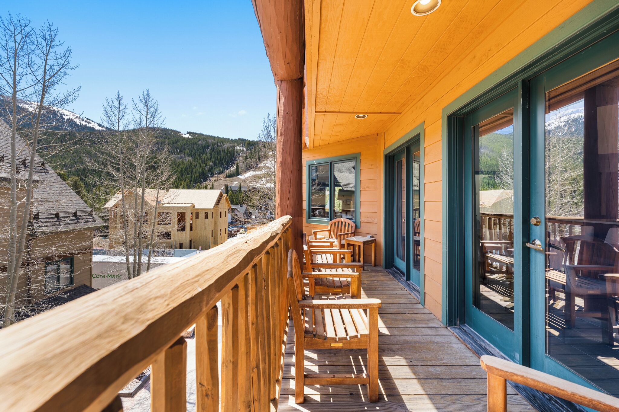 Una terraza de madera con asientos exteriores, con vistas a un paisaje montañoso.