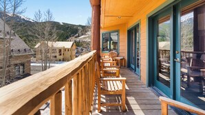 Una terraza de madera con asientos exteriores, con vistas a un paisaje montañoso.