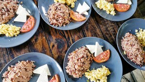 Multiple plates of food with rice, scrambled eggs, and tomato slices on a wooden table.