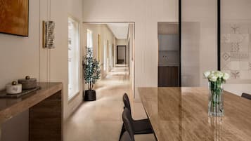Un interior moderno con un largo pasillo que conduce a un comedor con una mesa y sillas de mármol.