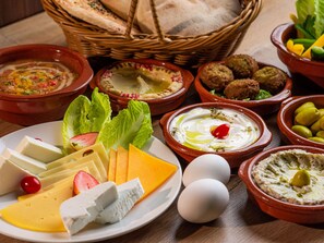 Diversos alimentos, entre quesos, aceitunas y salsas, sobre una mesa.