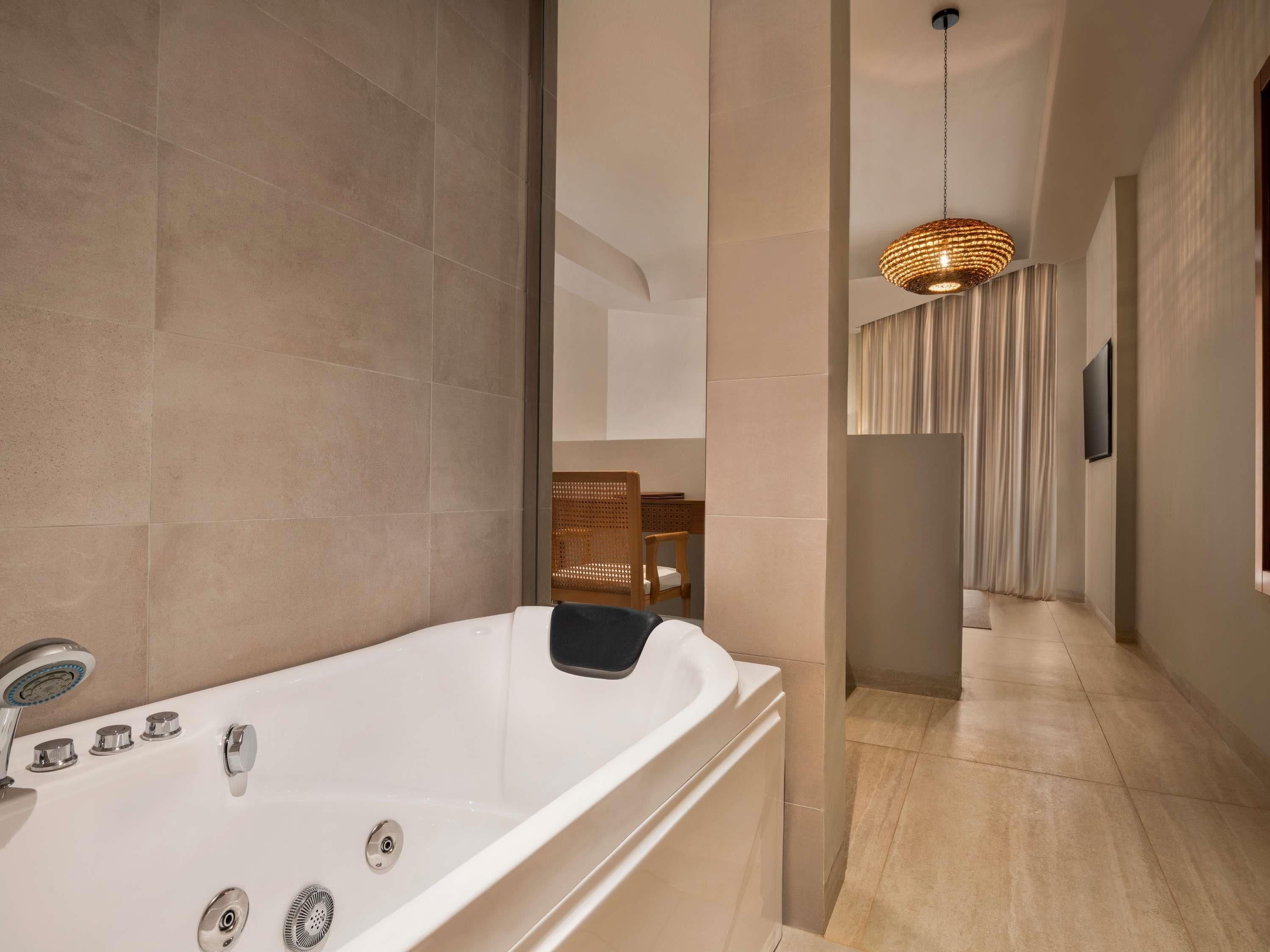 A modern bathroom with a large bathtub, a shower, and a hanging light fixture.