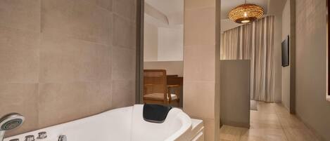 A modern bathroom with a large bathtub, a shower, and a hanging light fixture.