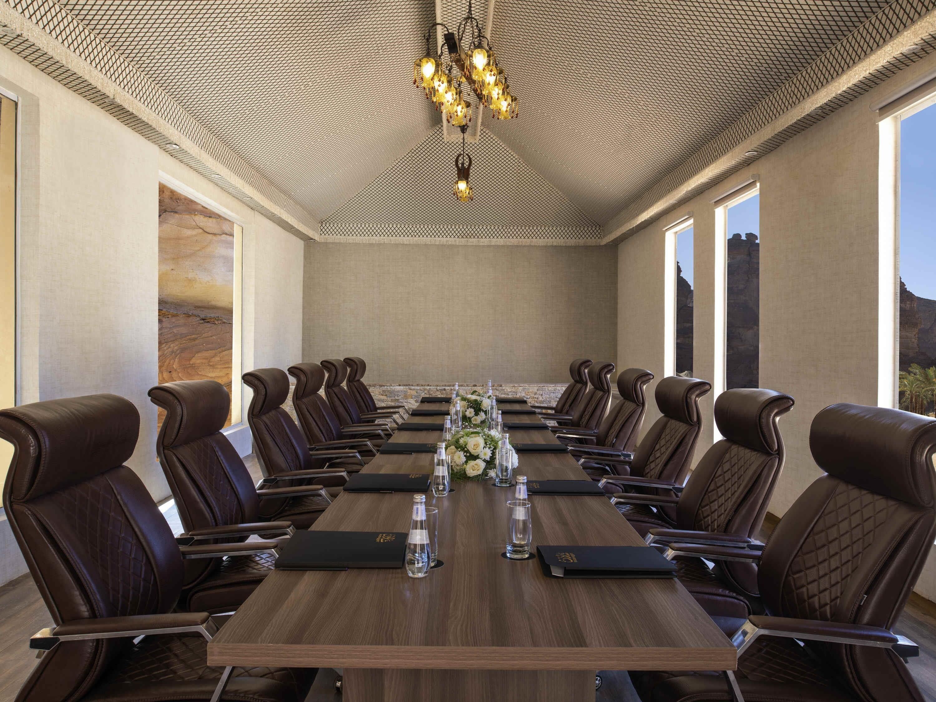 A conference room with a long table, leather chairs, and a chandelier.
