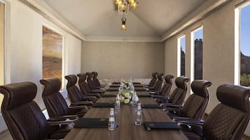 A conference room with a long table, leather chairs, and a chandelier.