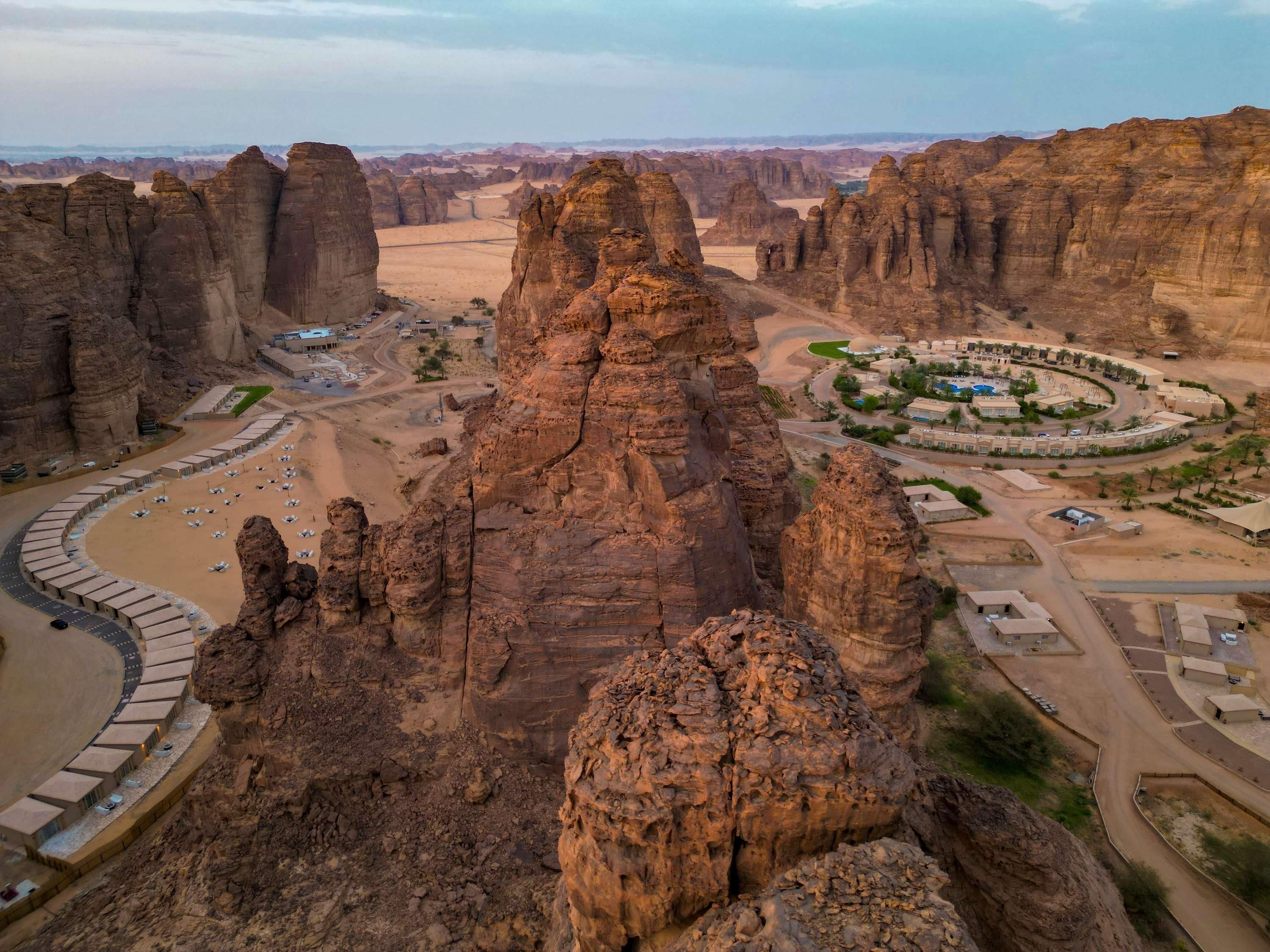 A desert landscape with prominent rock formations and a resort area with buildings and roads.