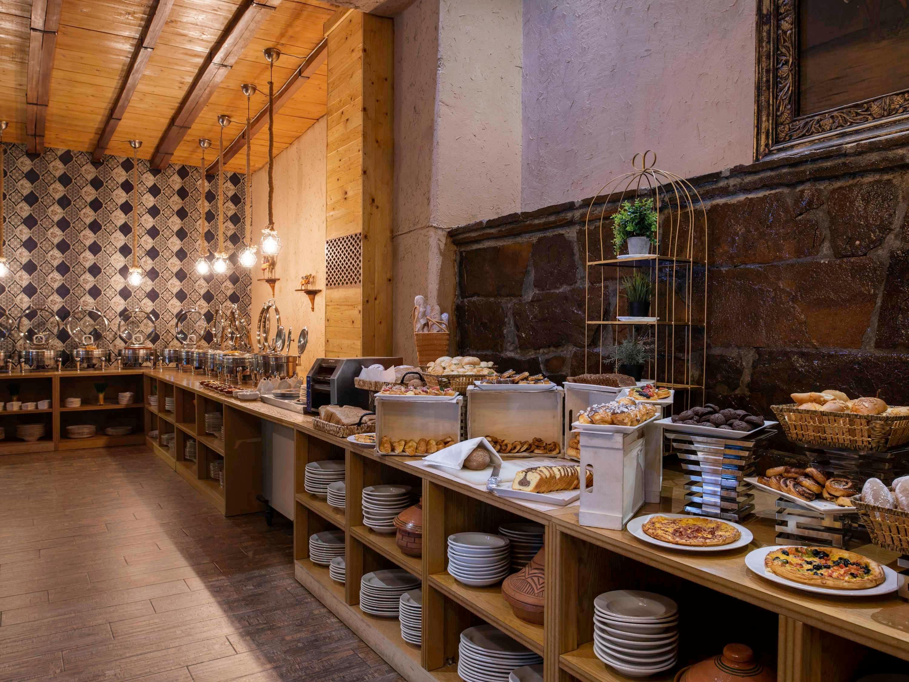 Montaje de bufé con diversos alimentos, una máquina de café y una pared con diseño.