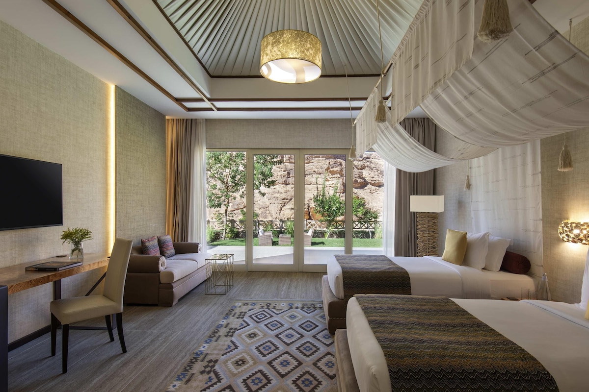 Habitación de hotel con una cama grande, un escritorio, una silla, un televisor y vistas al exterior.