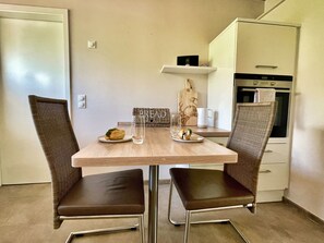 Una cocina compacta con una mesa de comedor y dos sillas, un microondas y un armario pequeño.