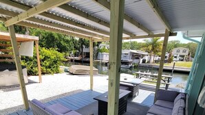 En overdækket terrasse med fletningsmøbler og udsigt til en lystbådehavn.