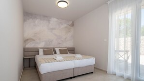 A modern bedroom with a large bed, a nightstand, and a ceiling light.