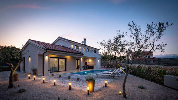 A modern two-story house with a swimming pool, outdoor lighting, and a garden.