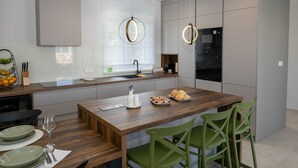 A modern kitchen with a wooden island, green chairs, and a built-in oven.