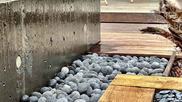 A concrete planter with a palm tree, wooden deck chairs, and a pebble pathway. - Villa Canopée 6P - Piscine Chauffée/fibre/clim (Gujan-Mestras)
