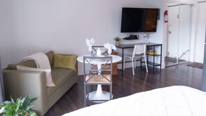A modern room with a sofa, a dining table, and a TV. - Wanderlust | Studio Suite with Private Patio (Harrison Hot Springs)
