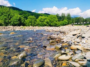 A clear river with rocks and a bridge in the background.