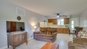 Ein Wohnzimmer mit Fernseher, Sofa und Couchtisch aus Holz.