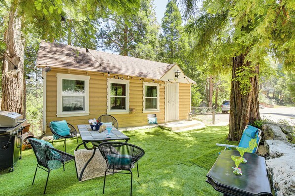 Una piccola baita di legno con patio, posti a sedere all'aperto e un barbecue.