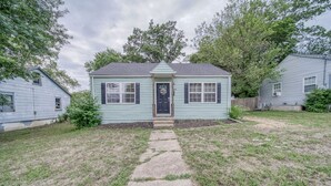 A small, single-story house with a front door, two windows, and a small porch.