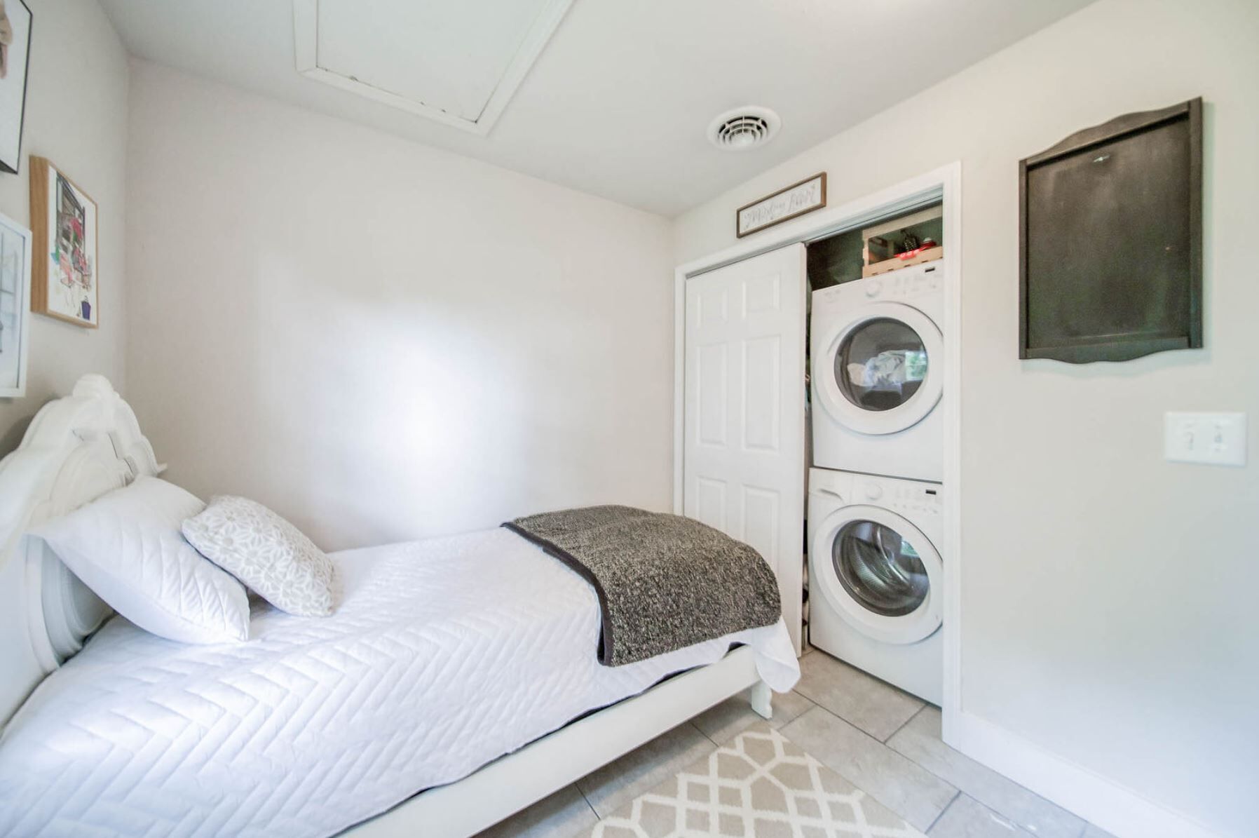 A bedroom with a bed, a washing machine, and a dryer.