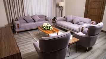 A modern living room with a sofa set, a coffee table with a floral centerpiece, and a lamp.