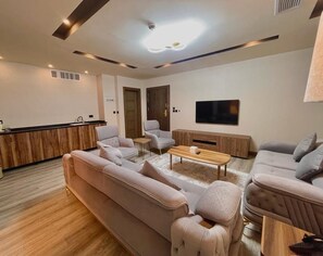 Una sala de estar moderna con un sofá, sillas, una mesa de centro y un televisor.