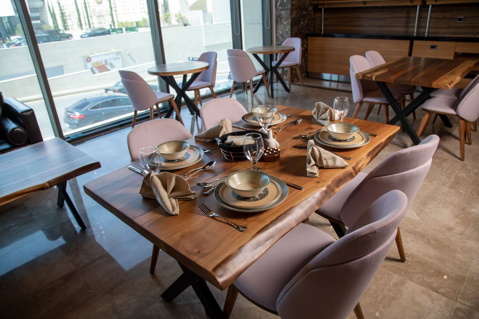 Un restaurante con una larga mesa de madera dispuesta para comer, equipada con platos, vasos y cubiertos.