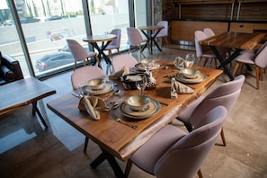 A restaurant with a long wooden table set for dining, equipped with plates, glasses, and cutlery. - Jeddah Homes Boutique Hotel (Amman)