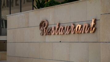 Fachada de edificio con un letrero tridimensional grande que dice 'Restaurant'.