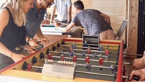 Un grupo de personas jugando al fútbol de mesa en una habitación con paredes de madera y una estructura de techo visible.