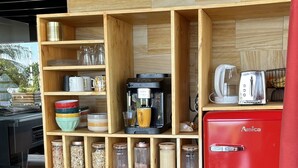 Una cocina compacta con estantes de madera, un refrigerador rojo y diversos electrodomésticos.