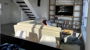 Un salon moderne avec un canapé, une bibliothèque, un téléviseur à écran plat et un escalier.