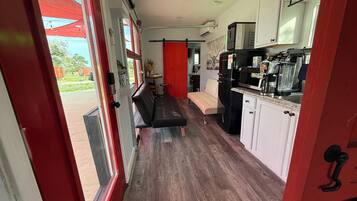 A compact kitchen with a bench, white cabinets, and a red accent wall.
