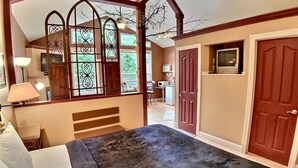 A bedroom with a large bed, a wooden bench, a desk, a TV, and a wardrobe. - Abbey Chateau Treehouse #10 / Oak Crest (Eureka Springs)