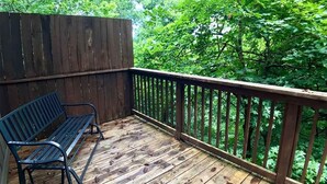A wooden deck with a bench and a wooden fence. - Abbey Chateau Treehouse #10 / Oak Crest (Eureka Springs)