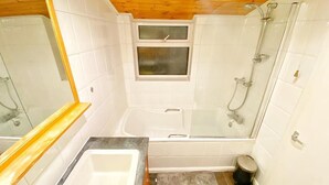 A bathroom with a bathtub, shower, and sink.