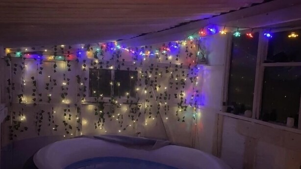A hot tub in a dimly lit room with string lights and hanging decorations.
