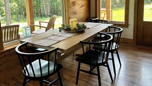 Un comedor de madera con una mesa larga, sillas negras y una lámpara colgante.