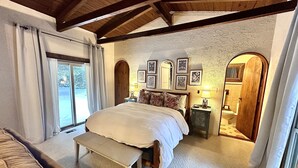 A bedroom with a large bed, a bench, a nightstand, and a mirror. There is a window with curtains and a view of the outdoors. - Trails Lodge retreat is steps from
The bar and ORV trails!!! (Harrison)