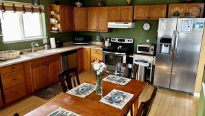 A kitchen with wooden cabinets, a stainless steel refrigerator, a microwave, an oven, and a sink. - Large Mountain Cabin → Black Hawk -> Amazing Views (Black Hawk)