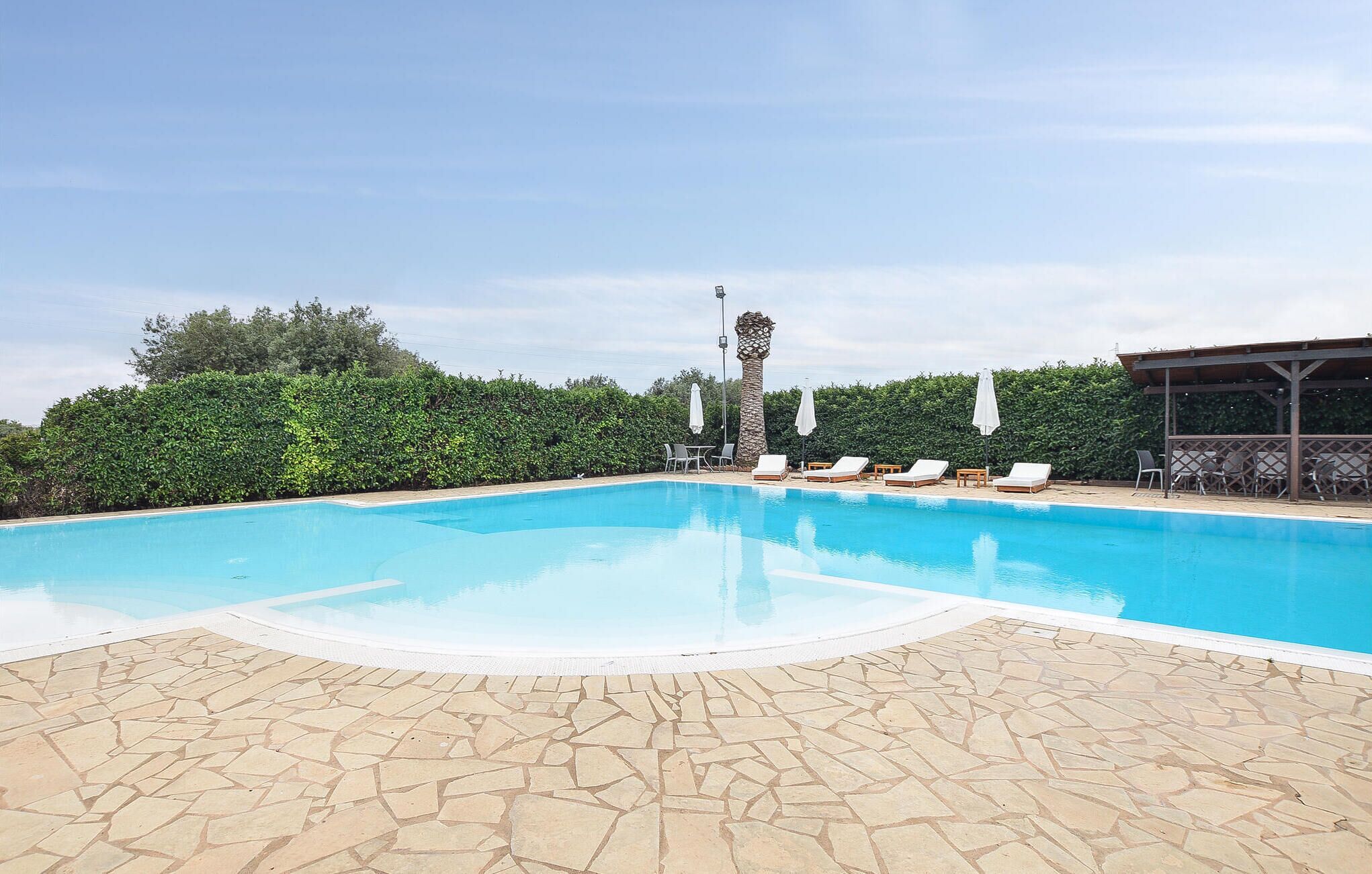 Une piscine avec des chaises longues et une pergola.