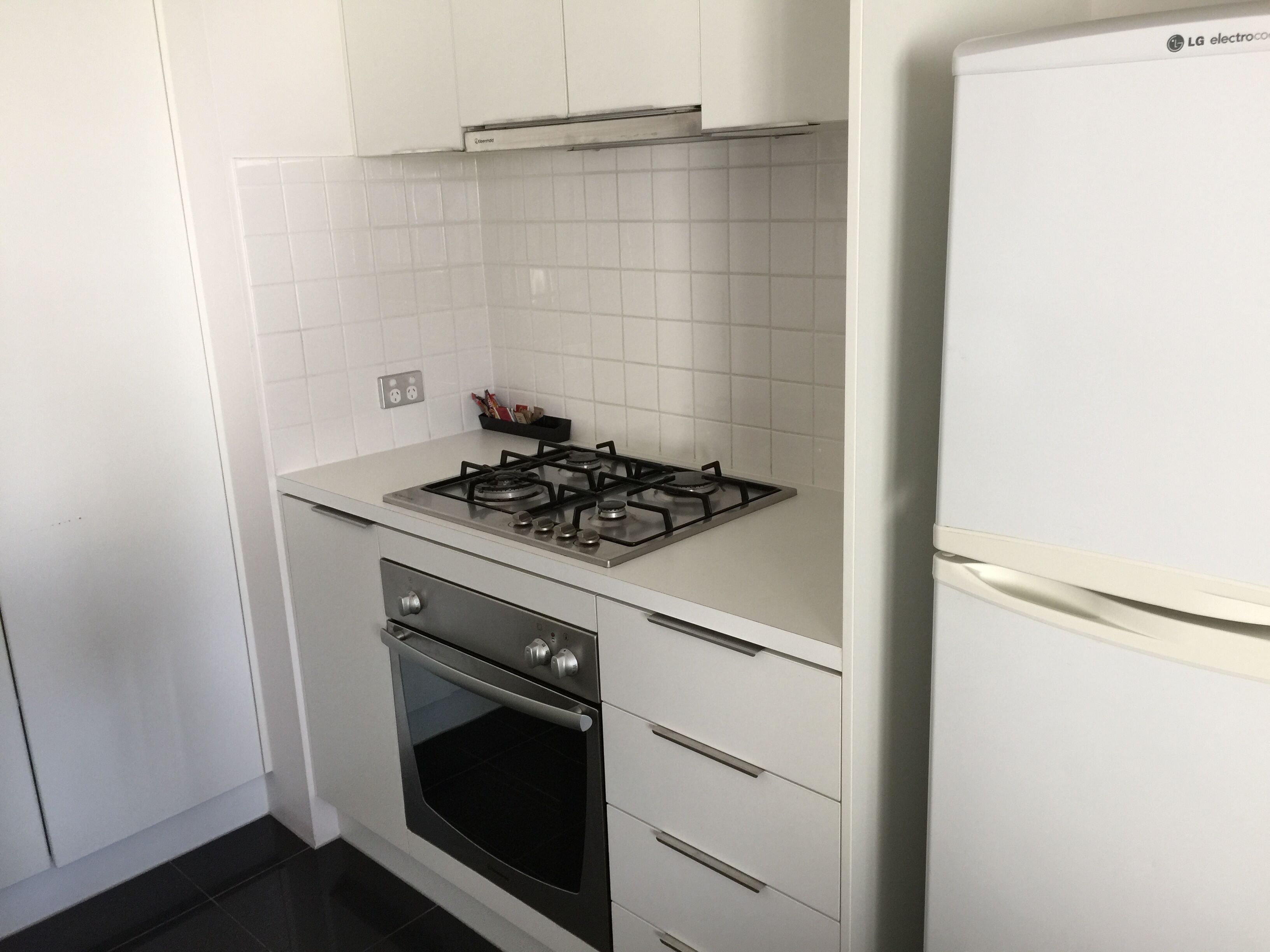 Una cocina compacta con estufa a gas, horno y refrigerador blanco.